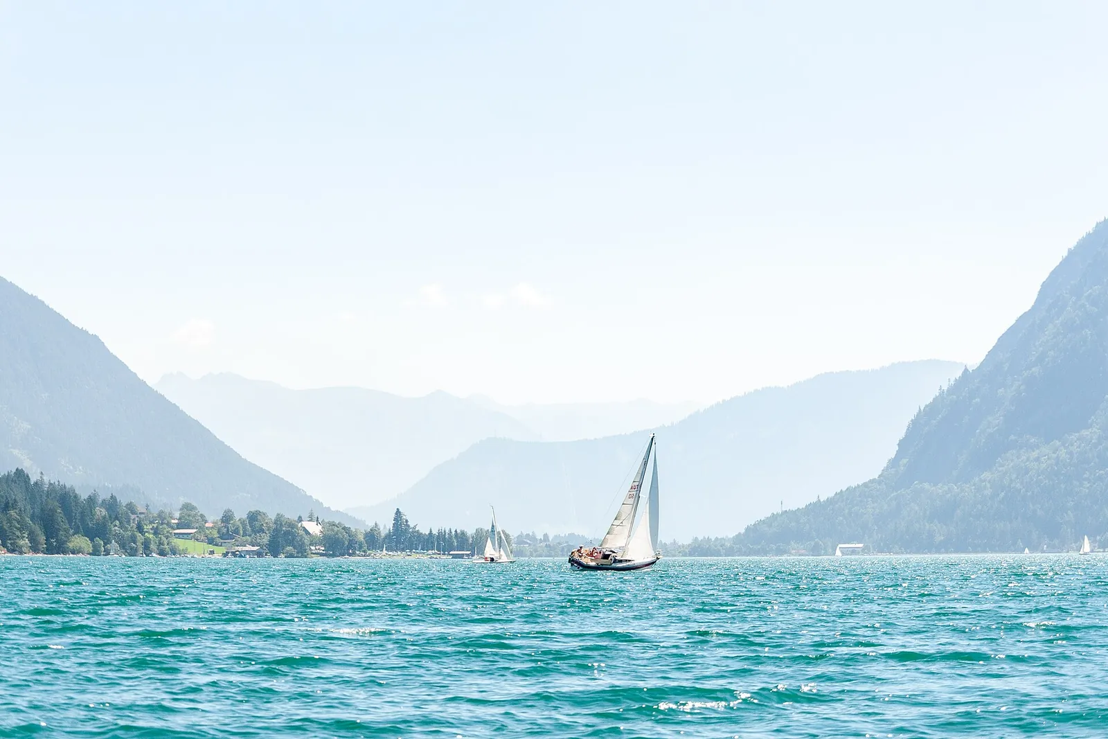 Segelboot auf dem türkisfarbenen Achensee in Tirol vor Bergkulisse